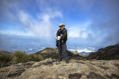 Portrait of male hiker standing on mountain against sky