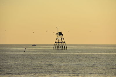 Silhouette bird flying over sea against clear sky