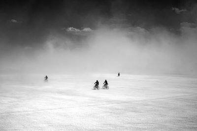 Silhouette of people walking on snow covered field