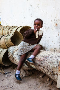 Portrait of young woman sitting on wall