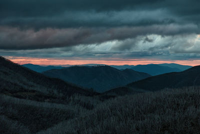 Scenic view of mountains against cloudy sky during sunset