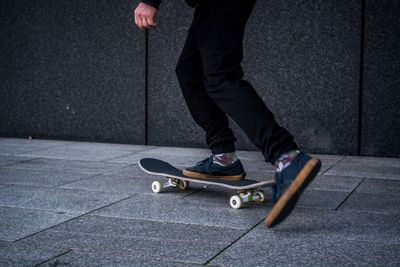 Low section of man using skateboard on sidewalk