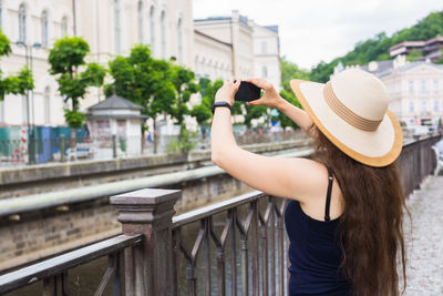 Rear view of woman standing by railing in city