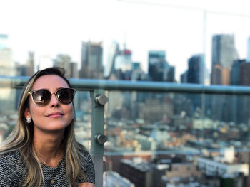 Portrait of smiling woman against buildings in city