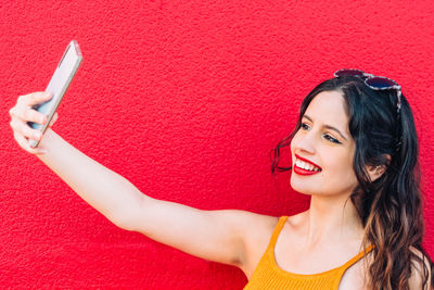 Portrait of a smiling young woman against red background