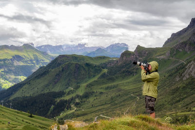 Man photographing on mountain against sky