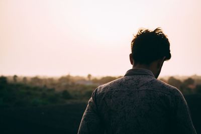 Rear view of man standing against clear sky