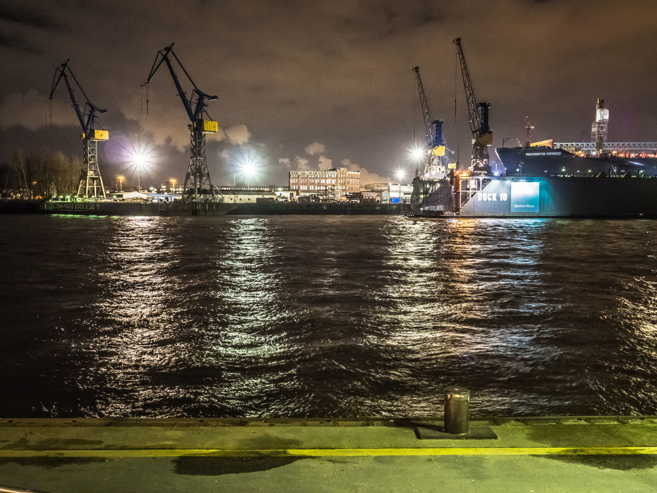 VIEW OF ILLUMINATED COMMERCIAL DOCK AT NIGHT