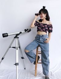 Full length of young woman photographing against wall