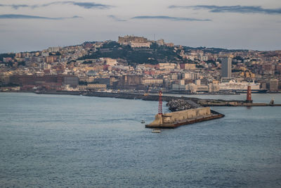 Sailboat on sea by buildings in city against sky