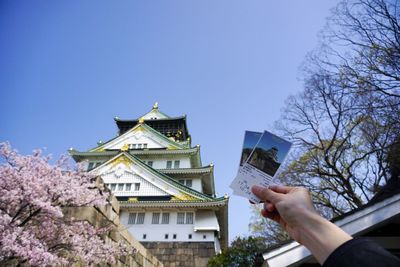 Low angle view of man holding built structure against clear sky