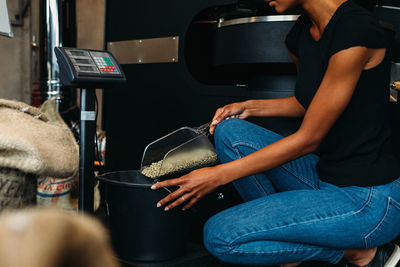 Midsection of woman pouring coffee beans in container