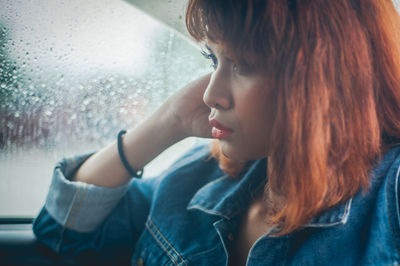 Close-up of young woman with water in window