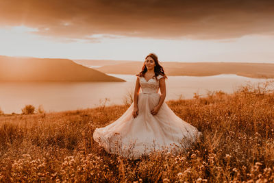 Rear view of woman standing on field against sky during sunset