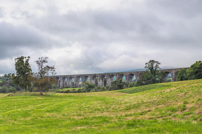 View of arch bridge on field against sky