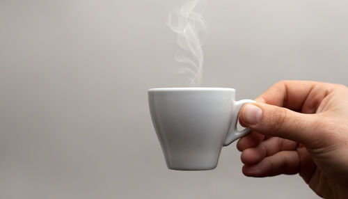 Midsection of person holding coffee cup against white background