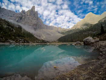 Scenic view of lake by mountains against sky