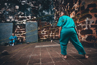 Rear view of man standing against graffiti wall