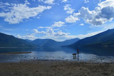 Rear view of silhouette man by lake against sky