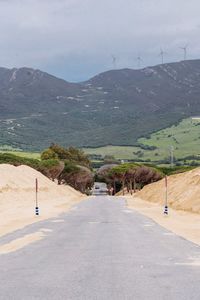 Road leading towards mountains against sky dunes