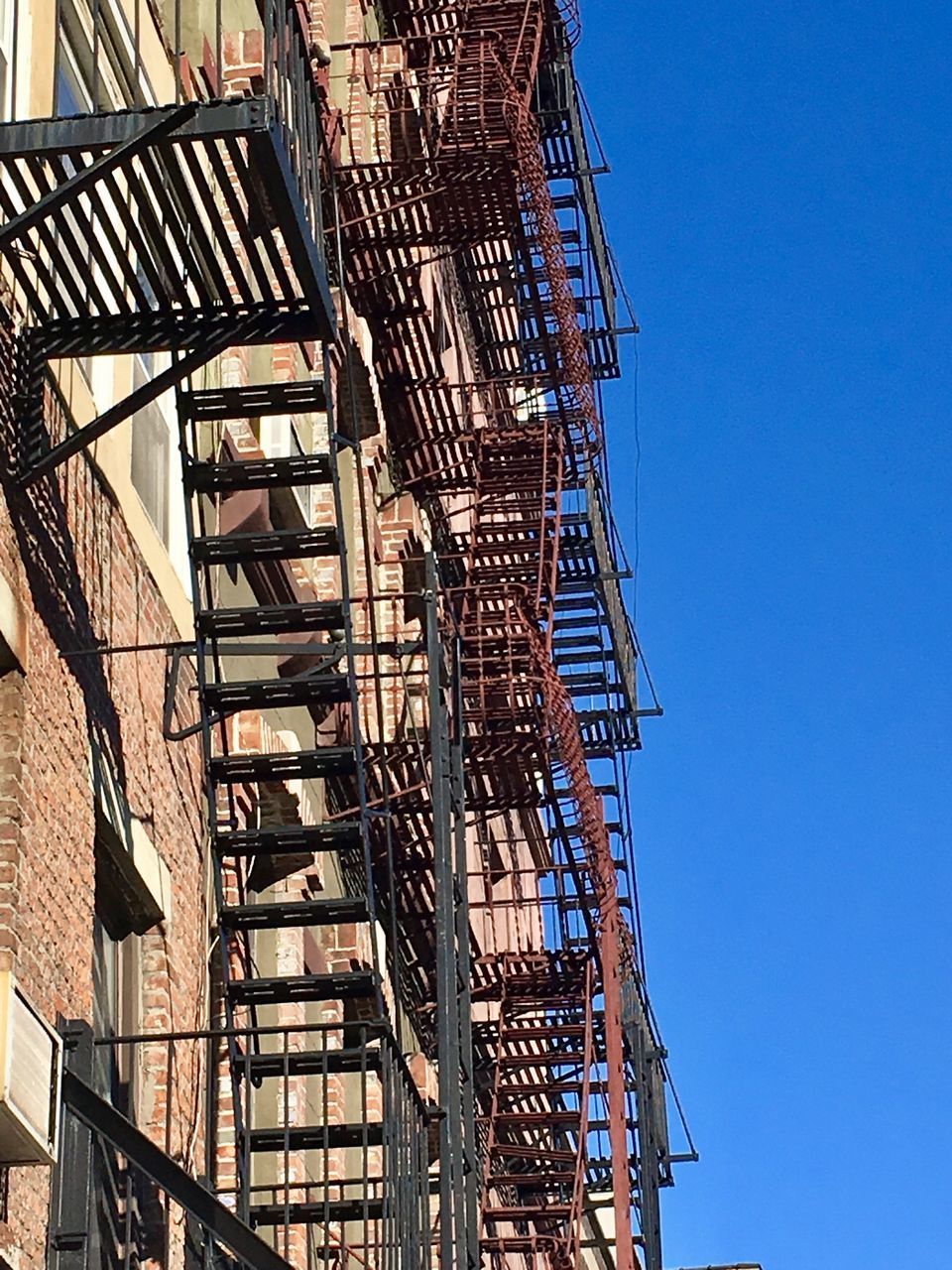 LOW ANGLE VIEW OF STAIRCASE AGAINST BLUE SKY