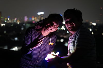 Man and woman holding illuminated lighting equipment at night