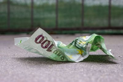 Close-up of crumpled paper currency on footpath