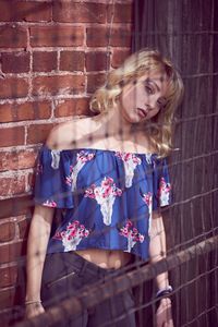 Young woman standing against brick wall