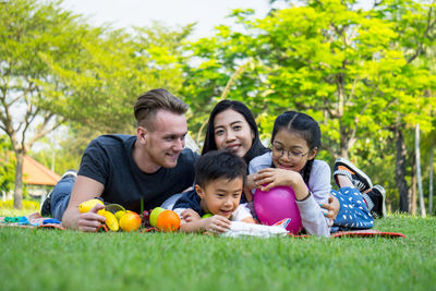 Happy family resting on grassy field at park