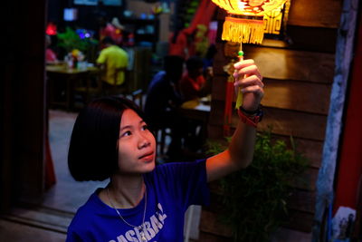 Close-up of young woman holding lantern at night