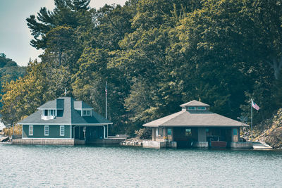 House by lake and trees against sky