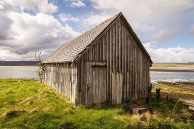 Wooden hut on field against sky
