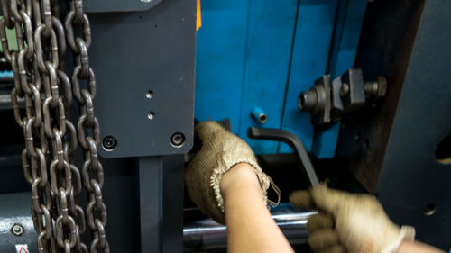 Cropped hands of woman repairing machine in workshop