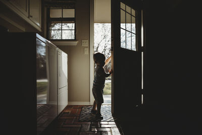 Side view of silhouette baby boy standing at doorway