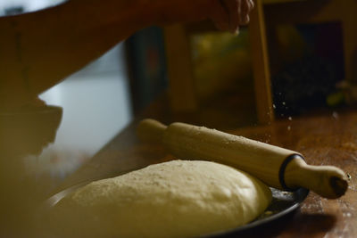Cropped hand sprinkling flour on dough