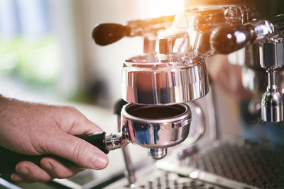 Cropped hand of man making coffee in cafe
