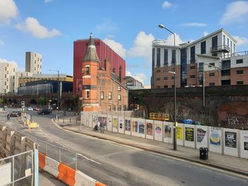 Road by buildings against sky in city