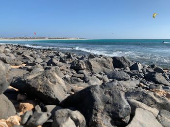 Rocks on beach against clear blue sky