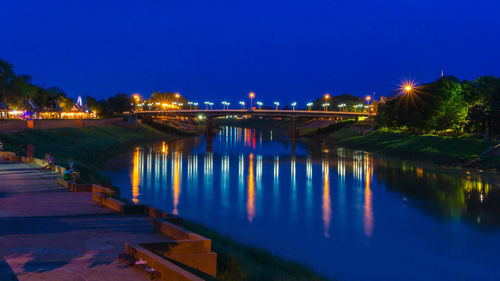 Illuminated bridge over river against sky at night