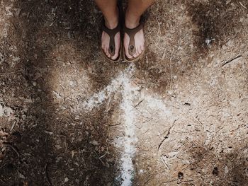 Low section of woman standing by arrow symbol on ground