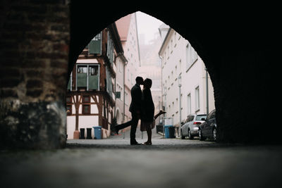 Full length of silhouette man standing by building in city