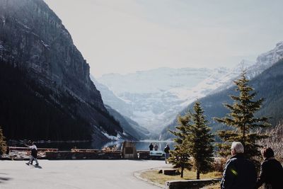 People on street by snowcapped mountain against sky