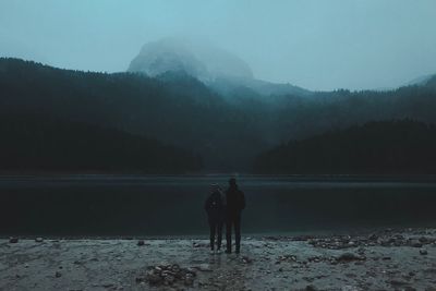 Rear view of silhouette people against mountain during winter