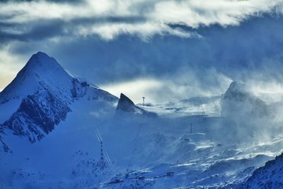 Scenic view of snow covered mountains against cloudy sky