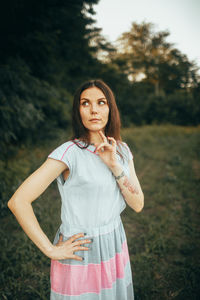 Portrait of young woman standing against trees