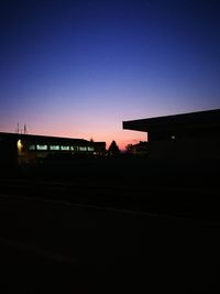 Silhouette buildings against clear sky at dusk