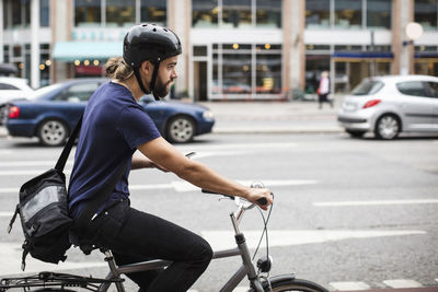 Side view of man cycling on city street