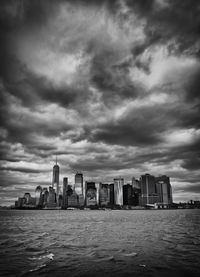 City at waterfront against cloudy sky