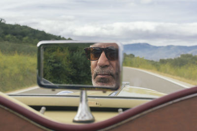 Reflection of man seen in a rear view mirror of car