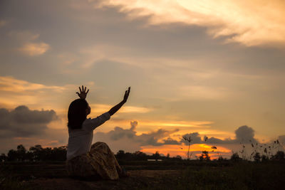 Silhouette woman standing on field against sky during sunset